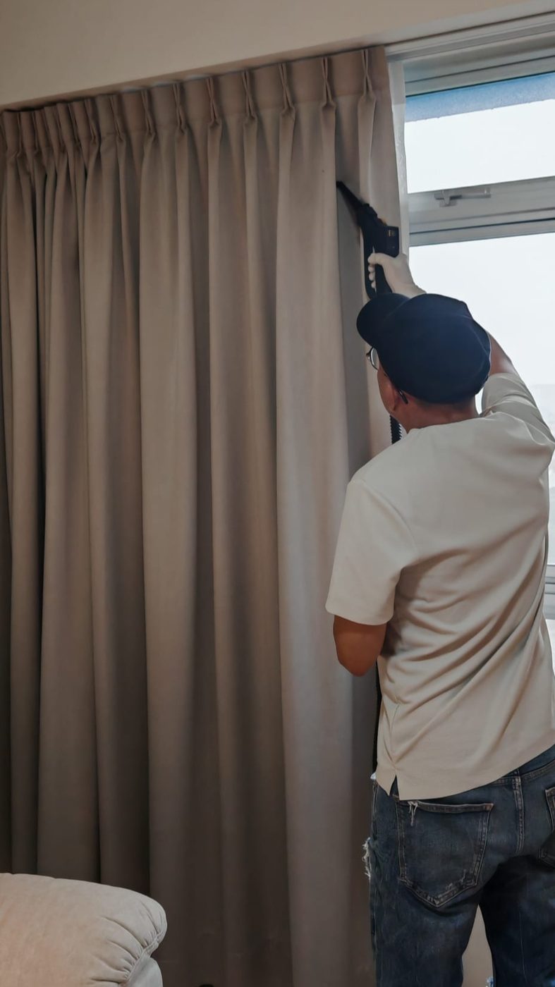 UltraRevive technician on-site cleaning curtains by a window in Singapore